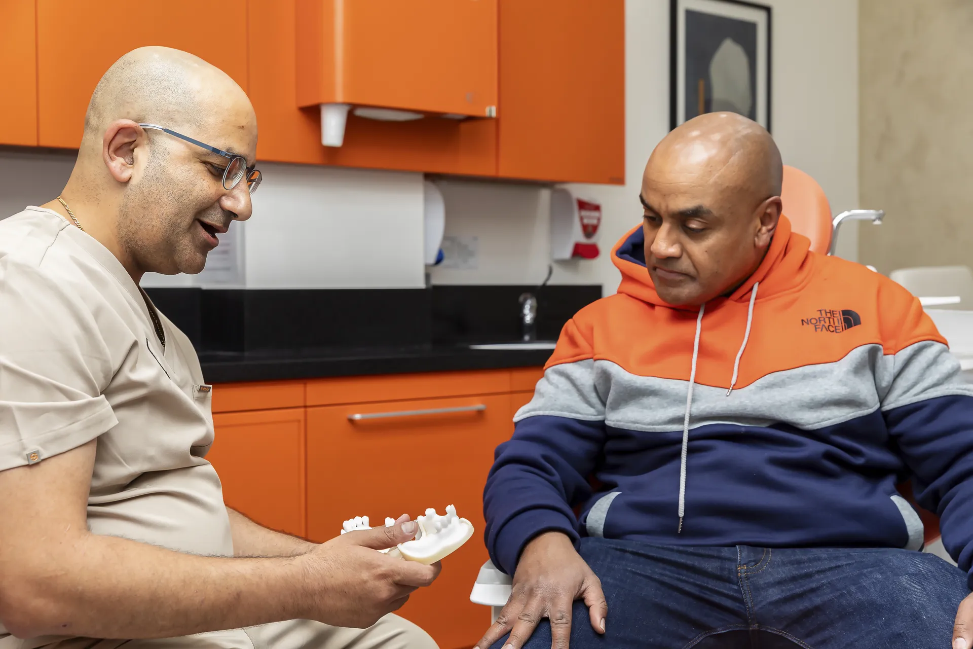 Dentist explaining a dental model to a seated patient
