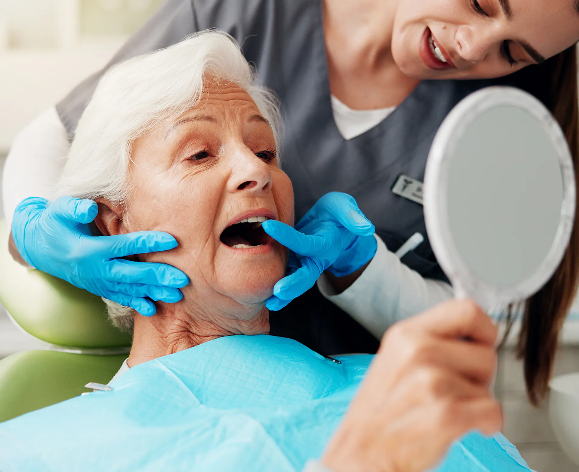 Dental nurse helping a patient check her new teeth in a hand mirror